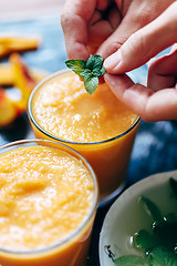 Image showing Person decorates orange smoothie