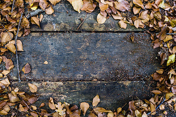 Image showing Background with old wooden table and yellow autumnal leaves