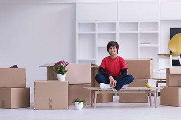 Image showing boy sitting on the table with cardboard boxes around him