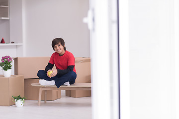 Image showing boy sitting on the table with cardboard boxes around him