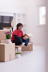 Image showing boy sitting on the table with cardboard boxes around him