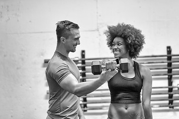 Image showing black woman doing bicep curls with fitness trainer