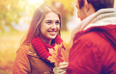 Image showing happy couple with maple leaves in autumn park