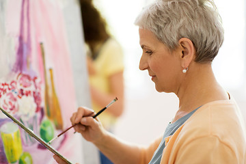 Image showing senior woman artist painting at art school