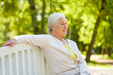 Image showing happy senior woman sitting on bench at summer park