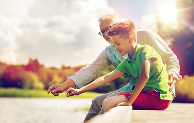 Image showing grandfather and grandson sitting on river berth