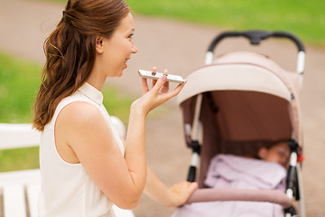 Image showing happy mother with smartphone and stroller at park