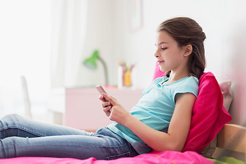 Image showing smiling girl texting on smartphone at home