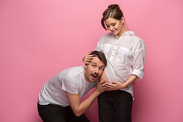 Image showing Handsome man is listening to his beautiful pregnant wife\'s tummy and smiling