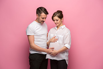 Image showing Handsome man is listening to his beautiful pregnant wife\'s tummy and smiling