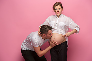 Image showing Handsome man is listening to his beautiful pregnant wife\'s tummy and smiling