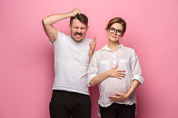 Image showing The funny surprised handsome man and his beautiful pregnant wife\'s tummy