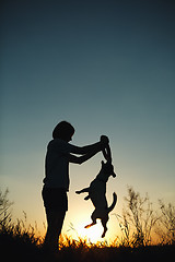 Image showing Silhouette of woman playing with a dog.