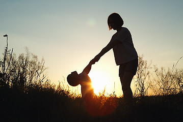 Image showing Silhouette of a woman with her child at sunset.