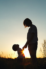 Image showing Silhouette of a woman with her child at sunset.