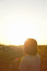 Image showing Girl inflates soap bubbles.