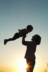 Image showing Silhouette of a woman with her child at sunset.