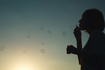 Image showing Girl inflates soap bubbles.
