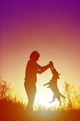 Image showing Silhouette of woman playing with a dog.