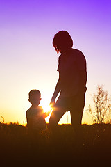 Image showing Silhouette of a woman with her child at sunset.