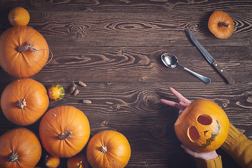 Image showing Hands holding Halloween pumpkin over wooden background