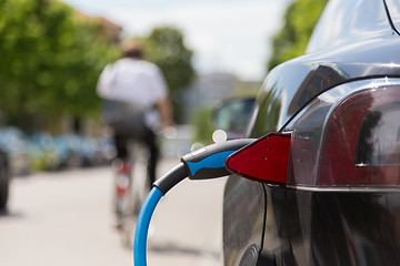 Image showing Power supply plugged into an electric car being charged.