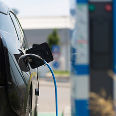 Image showing Power supply plugged into an electric car being charged.