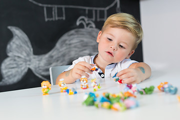 Image showing Portrait of cute toddler boy playing with toys at the desk at home.