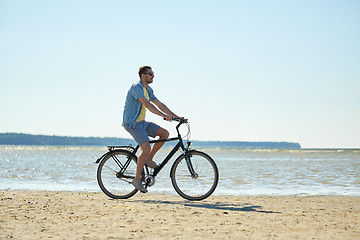 Image showing happy man riding bicycle along summer beach