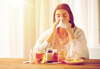 Image showing sick woman with medicine blowing nose to wipe