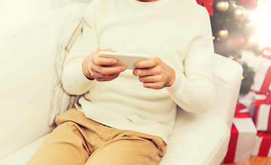 Image showing smiling man with smartphone at home for christmas