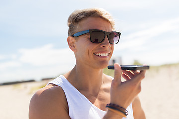 Image showing smiling man calling on smartphone at summer beach