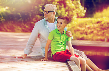 Image showing grandfather and grandson sitting on river berth