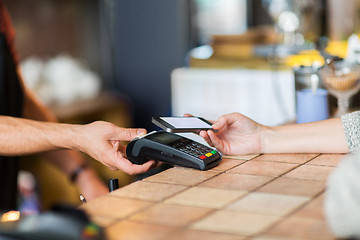 Image showing hands with payment terminal and smartphone at bar