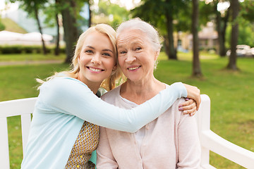 Image showing daughter with senior mother hugging on park bench