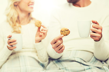 Image showing close up of happy couple with cookies and tea cups