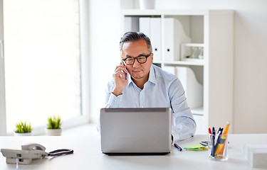 Image showing businessman with laptop calling on smartphone