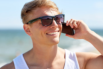 Image showing smiling man calling on smartphone on summer beach