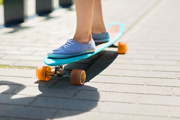 Image showing female legs riding on longboard along road