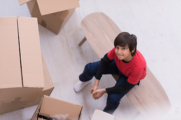 Image showing boy sitting on the table with cardboard boxes around him top vie