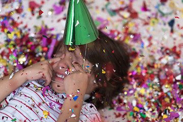 Image showing kid blowing confetti while lying on the floor