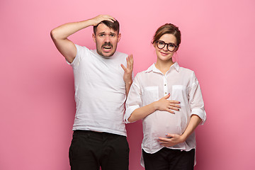 Image showing The funny surprised handsome man and his beautiful pregnant wife\'s tummy