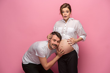 Image showing Handsome man is listening to his beautiful pregnant wife\'s tummy and smiling