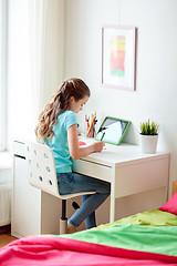 Image showing girl with tablet pc writing to notebook at home