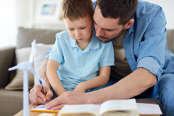 Image showing father and son with toy wind turbine at home