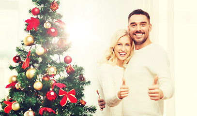 Image showing happy couple showing thumbs up with christmas tree