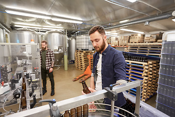 Image showing men with bottles on conveyor at craft beer brewery