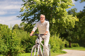 Image showing happy senior man riding bicycle at summer park