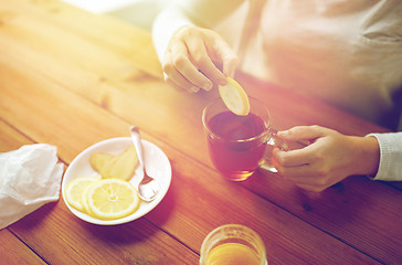 Image showing close up of woman adding lemon to tea cup