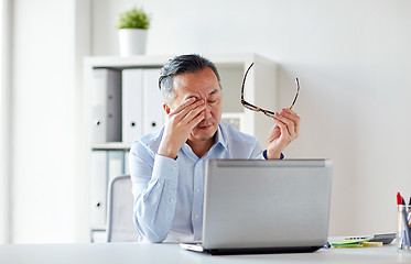 Image showing tired businessman with glasses at laptop in office